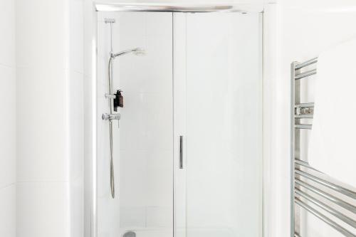 a shower stall with a glass door in a bathroom at Maitland House Boutique Apartment in Gloucestershire
