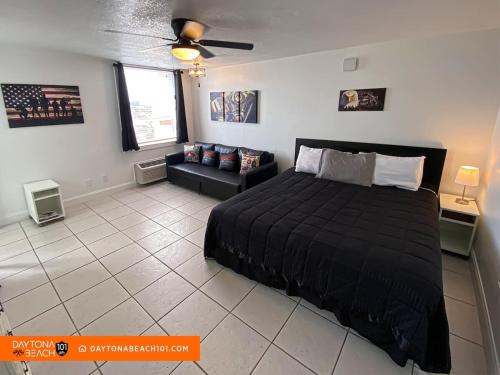 a bedroom with a black bed and a couch at Amazing Studio Steps Away From The Atlantic Ocean! in Daytona Beach
