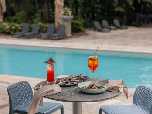 a table with a plate of food and drinks next to a pool at Pullman Palm Cove Sea Temple Resort & Spa in Palm Cove