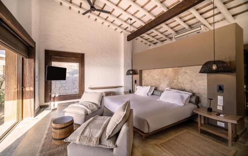 a bedroom with a bed and a couch and a tv at Inkaterra Cabo Blanco in Talara