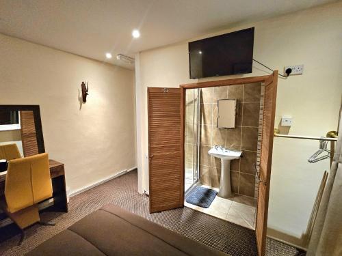a bathroom with a sink and a shower with a television on the wall at Hotel Claytou in Blackpool