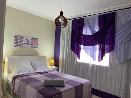 a bedroom with purple curtains and a bed with a window at Castelo Princesa Isabel in Ouro Preto