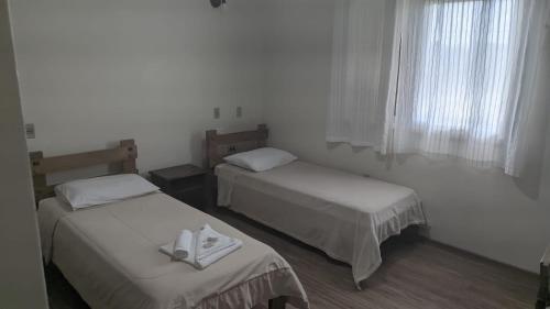 a room with two beds and a window at Cyro Palace Hotel Ltda in Caçapava do Sul