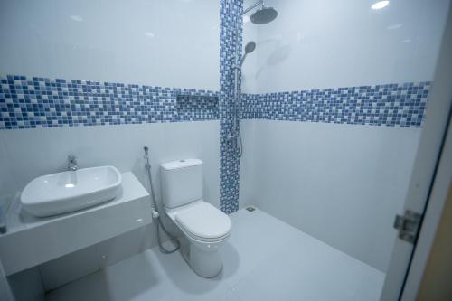 ein Badezimmer mit weißer Toilette und Waschbecken in der Unterkunft Azman in Fuvahmulah
