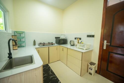 eine kleine Küche mit Spüle und Mikrowelle in der Unterkunft Azman in Fuvahmulah