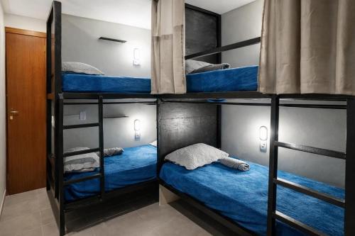 three bunk beds in a room with blue beds at Favela Hostel in Rio de Janeiro