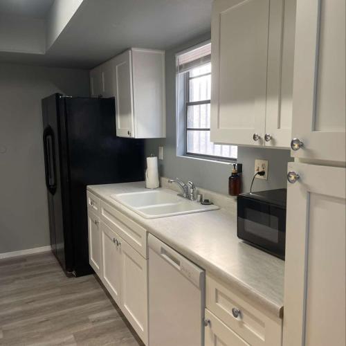 a kitchen with white cabinets and a black refrigerator at 2 or 3 Bedroom Extended Stay Walk to Strip MGM Casino Shop Club in Las Vegas