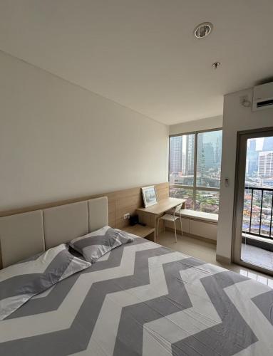 a bedroom with a bed and a desk and a window at Newton 1 CBD Jakarta Sudirman in Jakarta