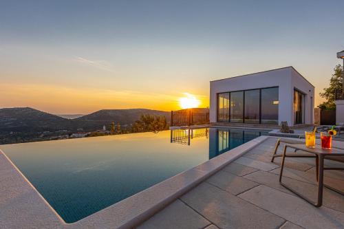 a villa with a swimming pool and a sunset at Villa 72 Crikvenica Riviera in Bribir