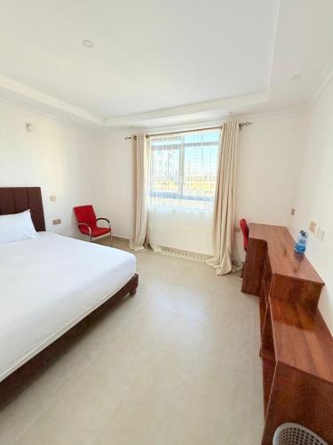 a bedroom with a bed and a desk and a window at Sacred Crown Suites in Naivasha