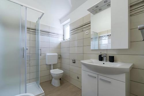 a white bathroom with a sink and a toilet at Casa Maja in Brtonigla