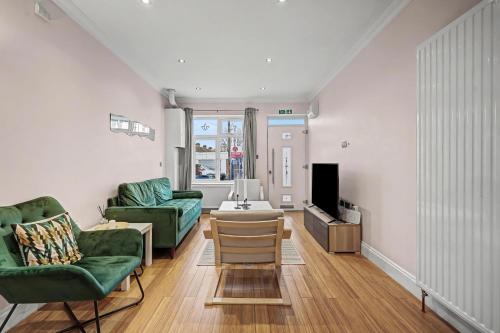 a living room with two green chairs and a tv at London Gem - Private Parking & Patio, 7m to Station in Streatham Vale