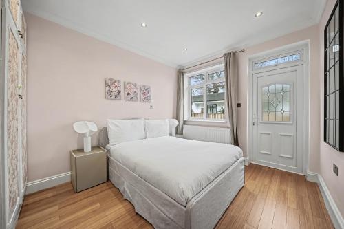 a white bedroom with a bed and a window at London Gem - Private Parking & Patio, 7m to Station in Streatham Vale