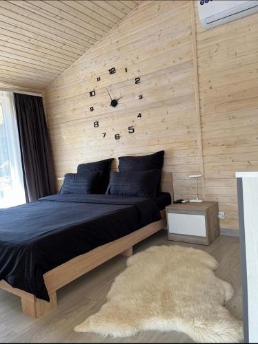a bedroom with a bed with a clock on the wall at Familyhata in Dzembronya