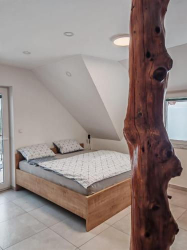 a bedroom with a bed and a wooden post at Apartma pod Tremi Kralji in Oplotnica