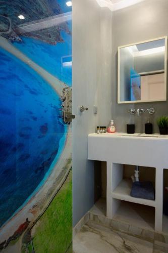 a bathroom with a sink and a painting of the ocean at Merovigli Suites in Mérikhas