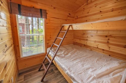 a bunk bed in a log cabin with a ladder at Sun Outdoors Frontier Town in Berlin