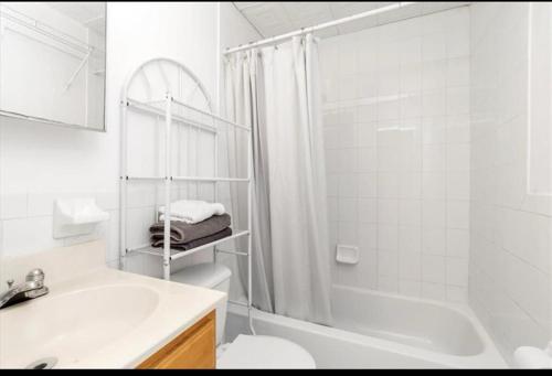 a white bathroom with a tub and a toilet and a sink at Large 3-Bedrooms/2-Bath Apt, One Block to Train in Brooklyn