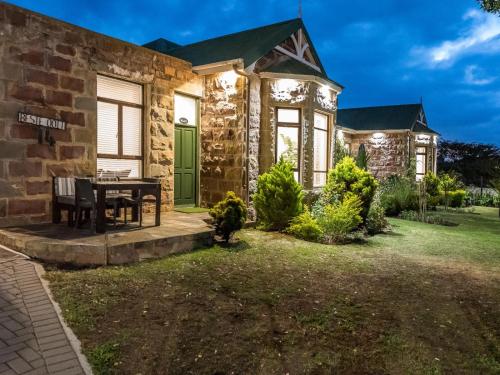 a stone house with a table in the yard at Lilla-Bett Self Catering Mossel Bay in Mossel Bay