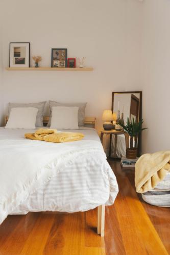 a bedroom with a white bed with a wooden floor at Habitación en vivienda compartida con baño privado in Santullán