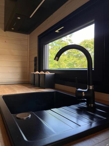 a kitchen with a black sink and a window at Tiny House Barujec in Brenna