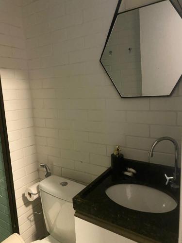 a bathroom with a sink and a toilet and a mirror at Estrela Do Mar flat Beach in Porto De Galinhas
