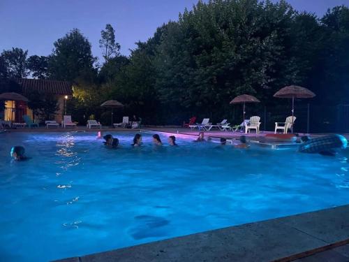 a group of people swimming in a pool at night at ZEcamping 3 étoiles - piscine chauffée haute saison in Antonne-et-Trigonant