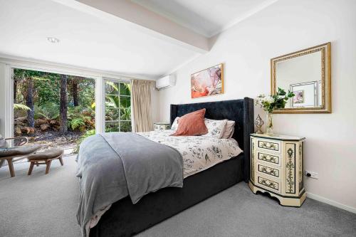 a bedroom with a bed and a table and a window at Bronte Cottage in Lawson