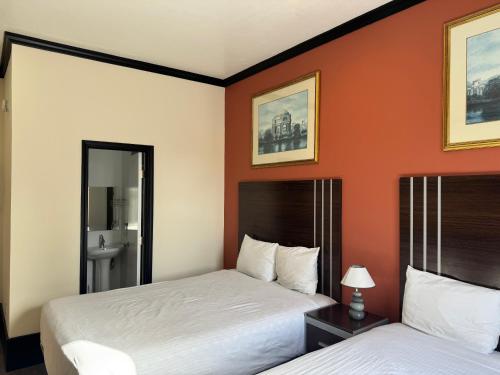 Zwei Betten in einem Hotelzimmer mit orangefarbenen Wänden in der Unterkunft Europa Hotel in San Francisco