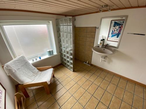 a bathroom with a sink and a chair and a shower at Ocean view from front parquet in Oyndarfjørður