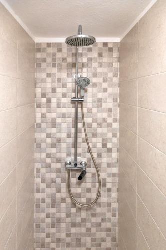 a shower in a tiled bathroom with a shower head at Apartment Sweet Studio in Punat
