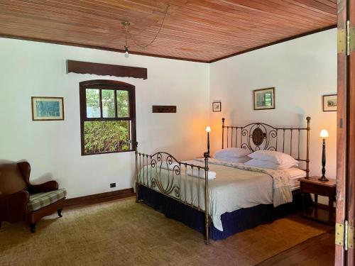a bedroom with a bed and a window and a chair at Sítio Mato Dentro in Atibaia
