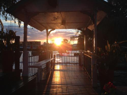 a sun setting behind a wooden boardwalk with benches at Cabañas Burdeos in Tigre
