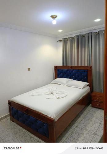 ein Schlafzimmer mit einem Bett mit blauem Kopfteil in der Unterkunft Nancy Real Estate in Limbe