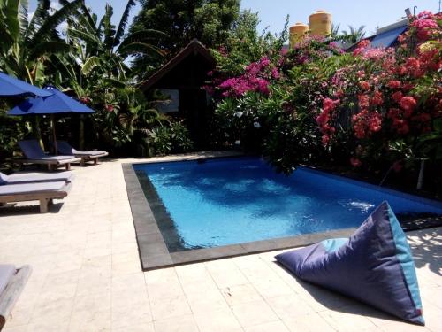 a swimming pool in a garden with flowers at Indigo Bungalows in Gili Trawangan
