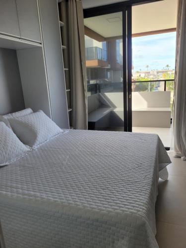 a bedroom with a white bed and a balcony at Cais Eco Residência in Ipojuca