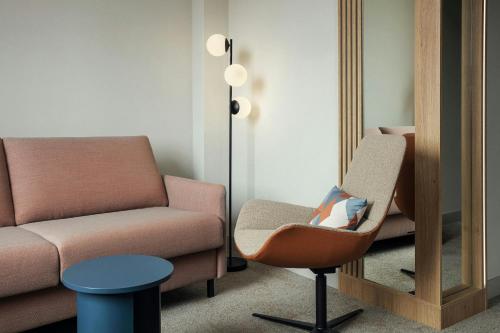 a living room with a chair and a mirror at Courtyard by Marriott Pilsen in Pilsen