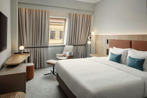 a hotel room with a large bed and a chair at Courtyard by Marriott Pilsen in Pilsen