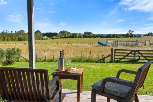 a patio with two chairs and a table and a field at Weld Cottage - Sustainable lifestyle property in New Plymouth