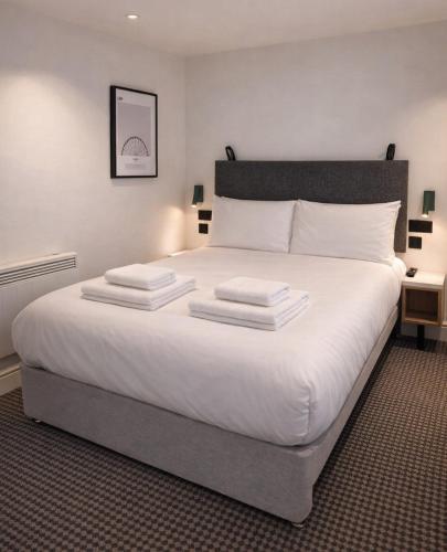 a bedroom with a large white bed with two pillows at Lidos Hotel in London