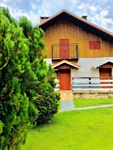 a house with a balcony and a green yard at Pousada Pinho Verde in Monte Verde