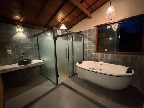 a bathroom with a tub and a glass shower at CASA VENTO SOLAR in Santana do Riacho