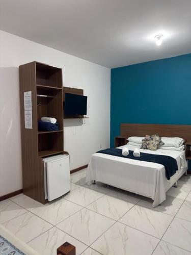 a bedroom with a bed and a blue wall at Canto da Praia Suítes in Arraial do Cabo