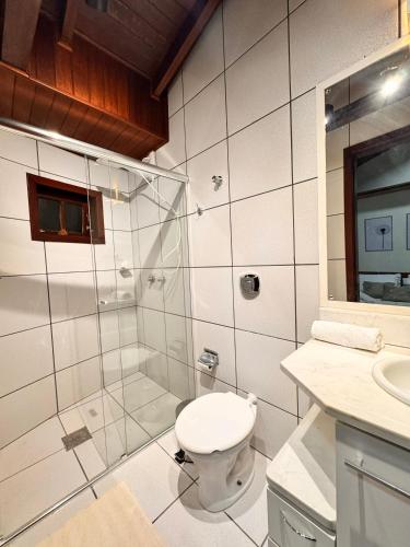 a bathroom with a toilet and a glass shower at Pousada Vivenza - Suíte 03 e 04 in Laguna