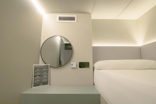 a small room with a bed and a mirror at Hostel Superlativo Trinidad in Málaga