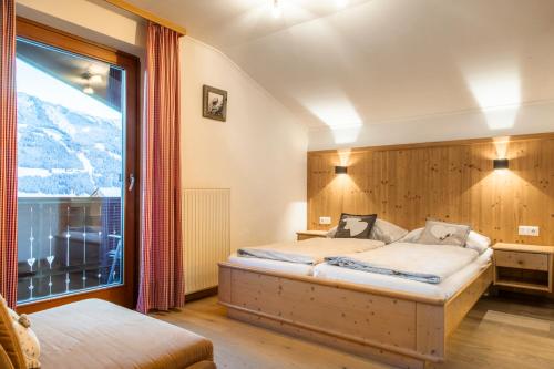 a bedroom with a bed and a large window at Bauernhof Grussberggut GRATIS THERME & SOMMERBERGBAHN in Bad Hofgastein
