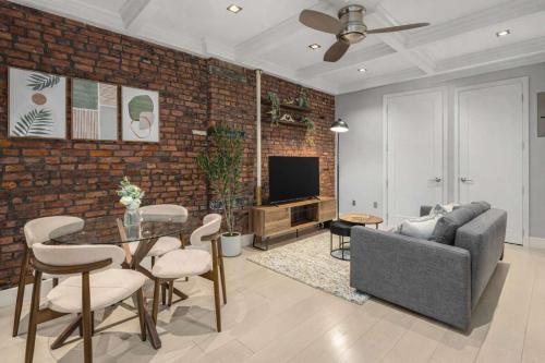 a living room with a brick wall and a couch and a table at Bold NYC Stay in Fashionable Nolita in New York