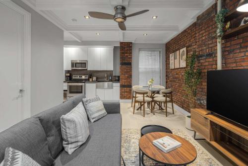 a living room with a gray couch and a kitchen at Bold NYC Stay in Fashionable Nolita in New York