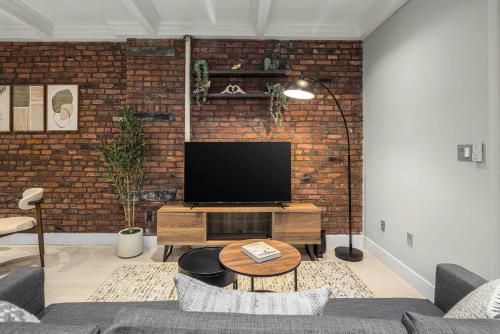 a living room with a tv on a brick wall at Bold NYC Stay in Fashionable Nolita in New York