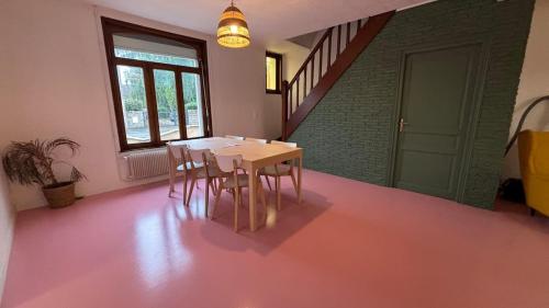 a table and chairs in a room with a pink floor at Grande Maison 17 personnes in Arras